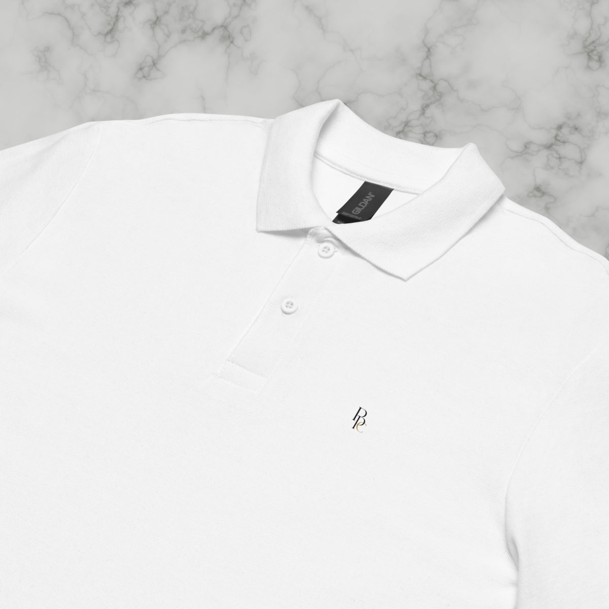 Col et broderie discrète d’un polo blanc posé sur marbre